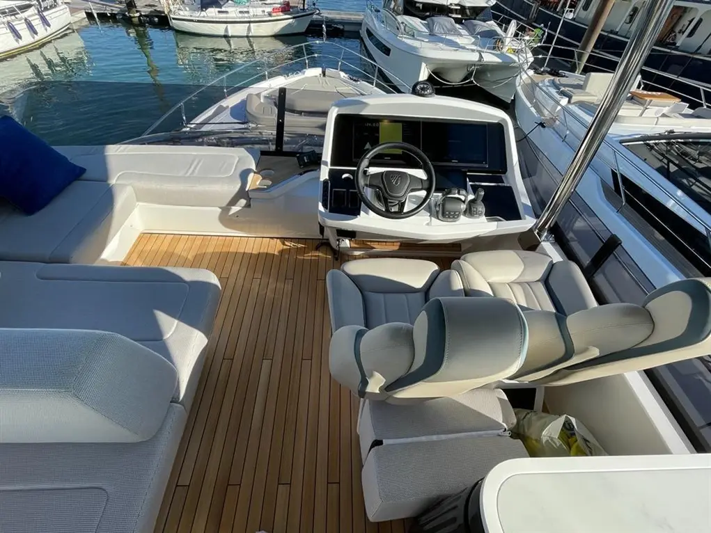 Luxury boat cockpit featuring sleek steering controls, comfortable seating, and a view of nearby moored vessels.